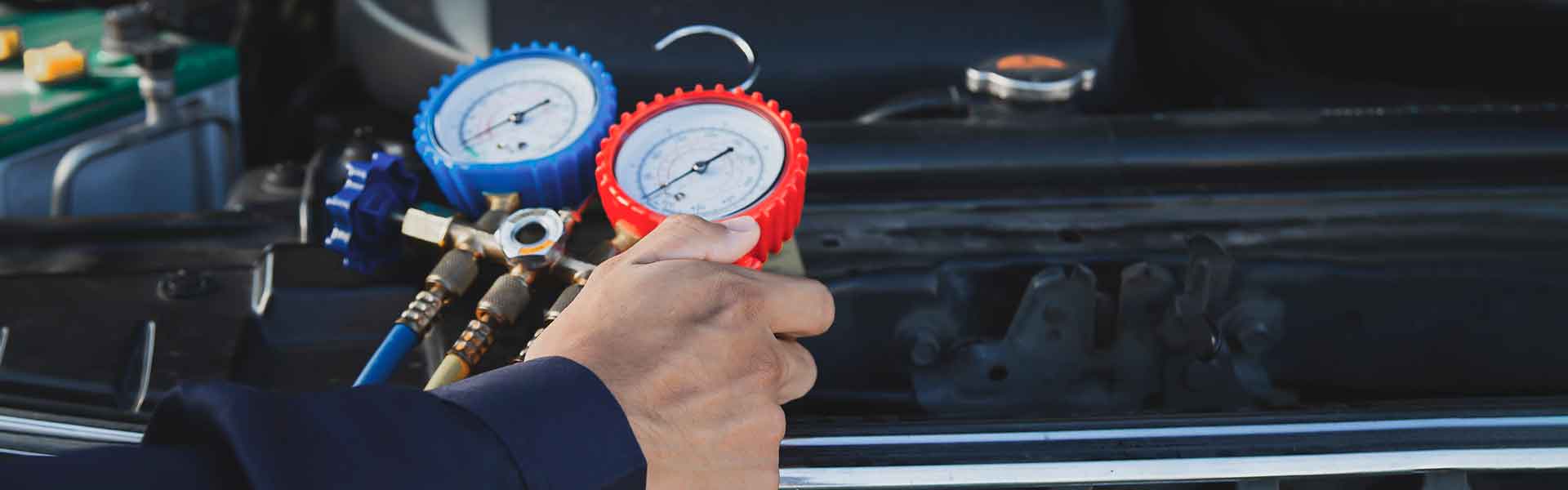 Technician checking car AC pressure gauges