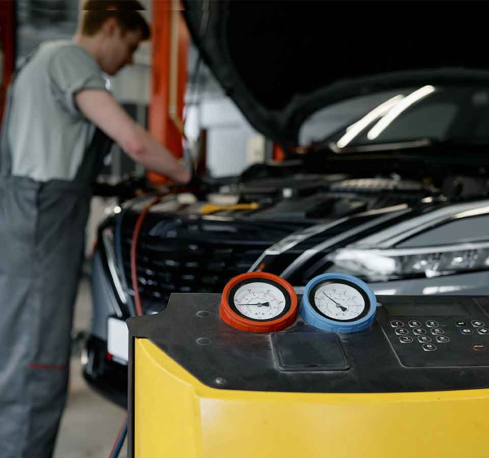 Auto Air Conditioning A/C Repair Denver Mechanic servicing car with air conditioning gauges