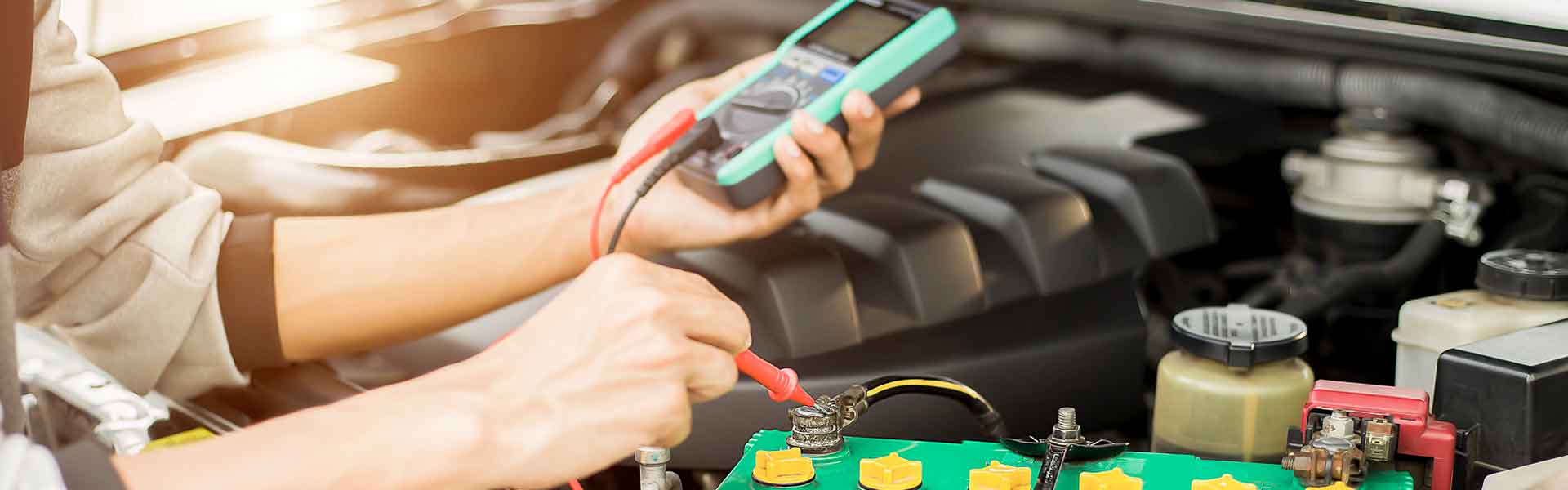 Technician testing car battery with multimeter