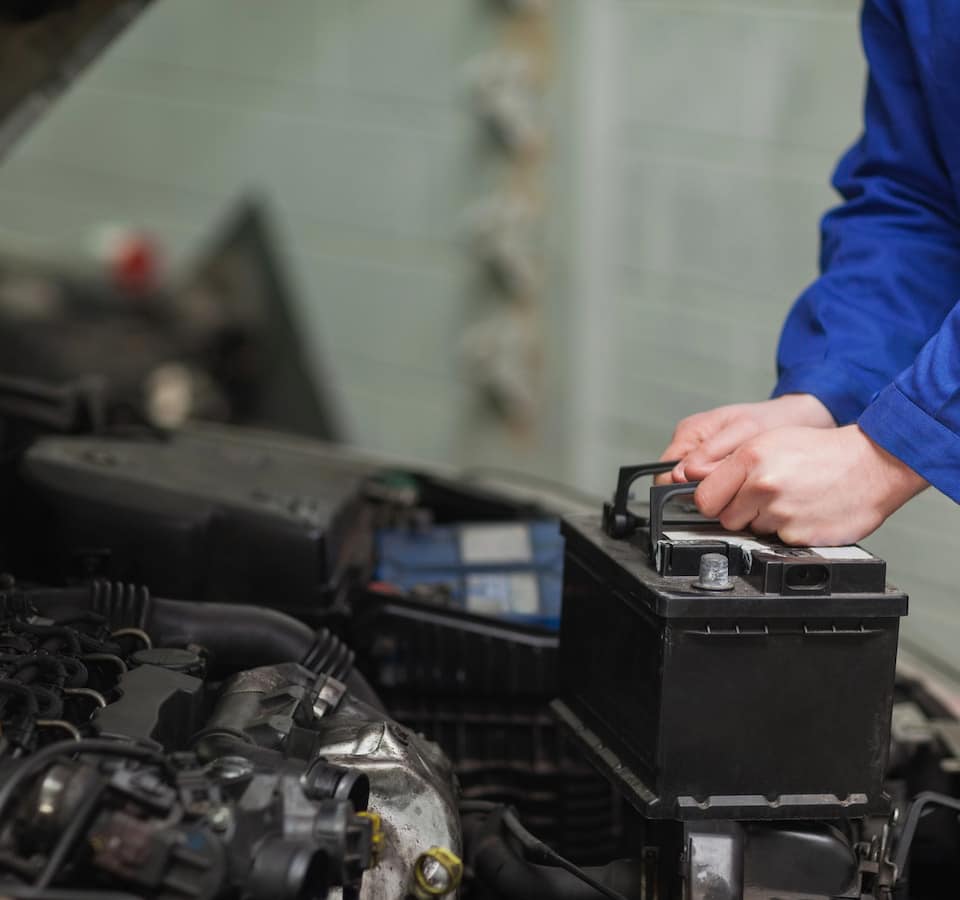 Auto Battery Service Repair Replacement Denver image Person installing car battery in engine bay