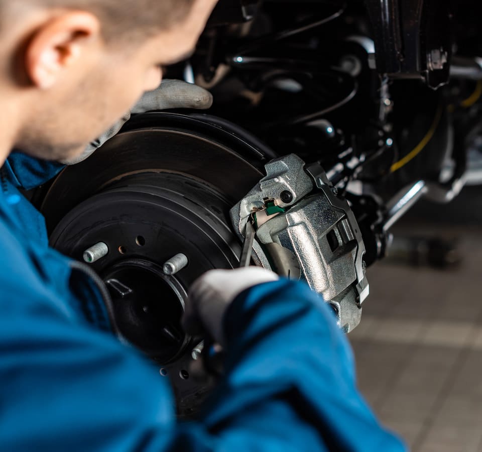Auto Brake Repair & Brake Fluid Change Denver image Mechanic repairing car brake caliper and rotor