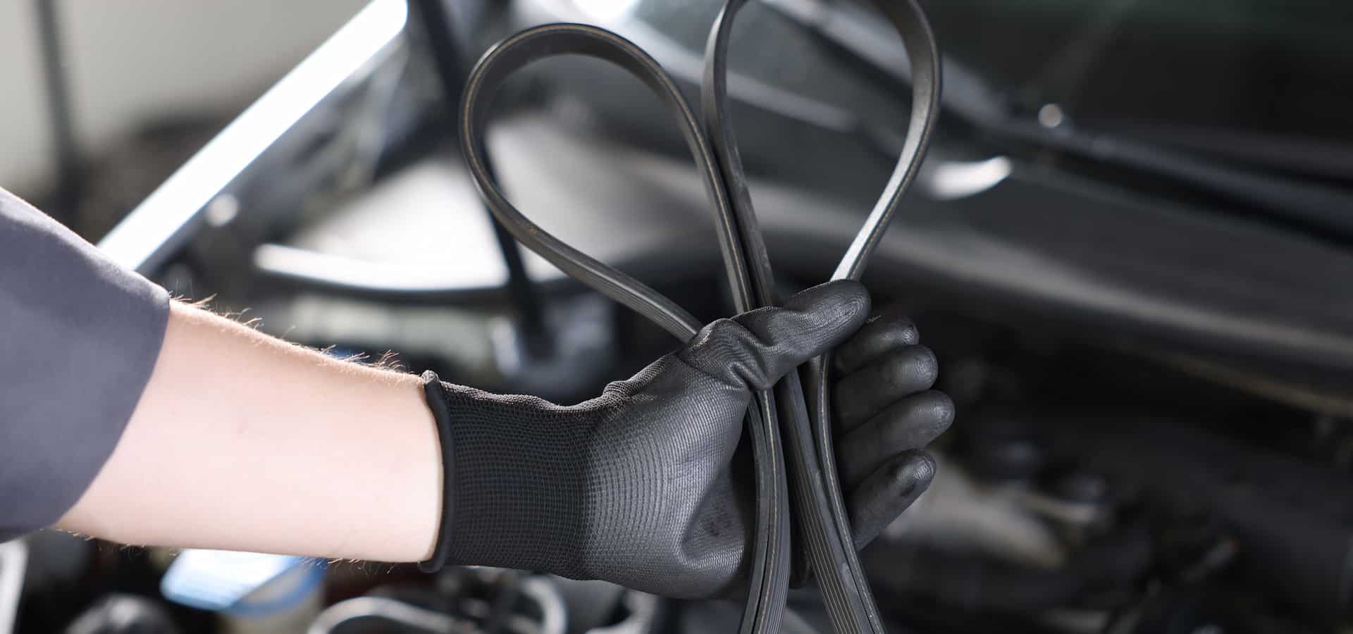 Gloved hand holding car serpentine belt