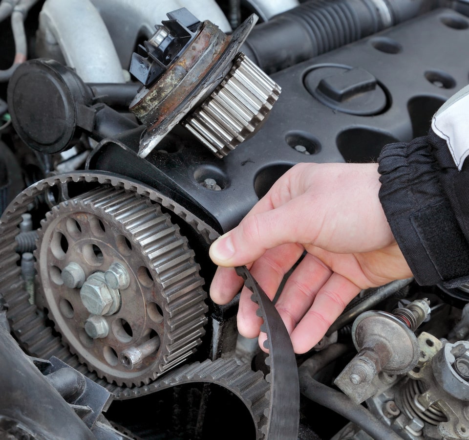 Auto Cambelt Timing Belt Replacement Denver image Hand removing worn timing belt from engine