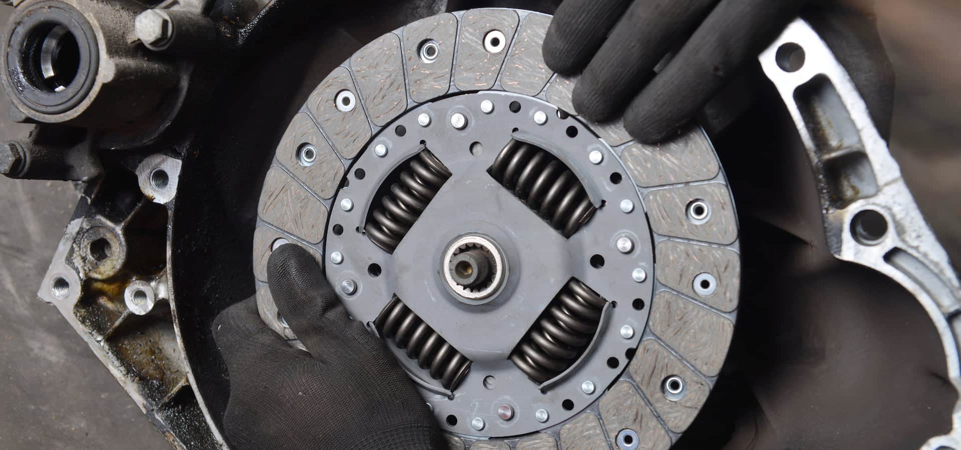 Mechanic holding car clutch disc near transmission