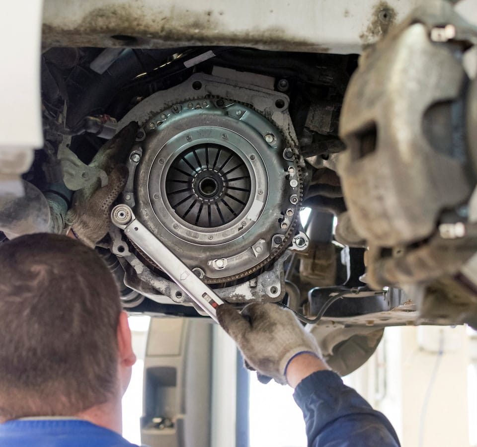 Auto Clutch Repair & Replacement Denver image Mechanic inspecting car clutch assembly underneath vehicle