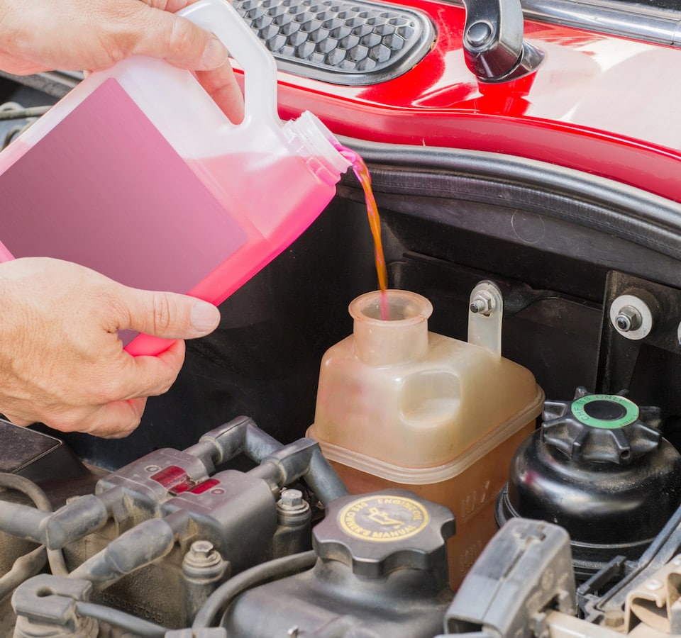 Auto Coolant Leak Repair Denver image Pouring pink coolant into car engine reservoir