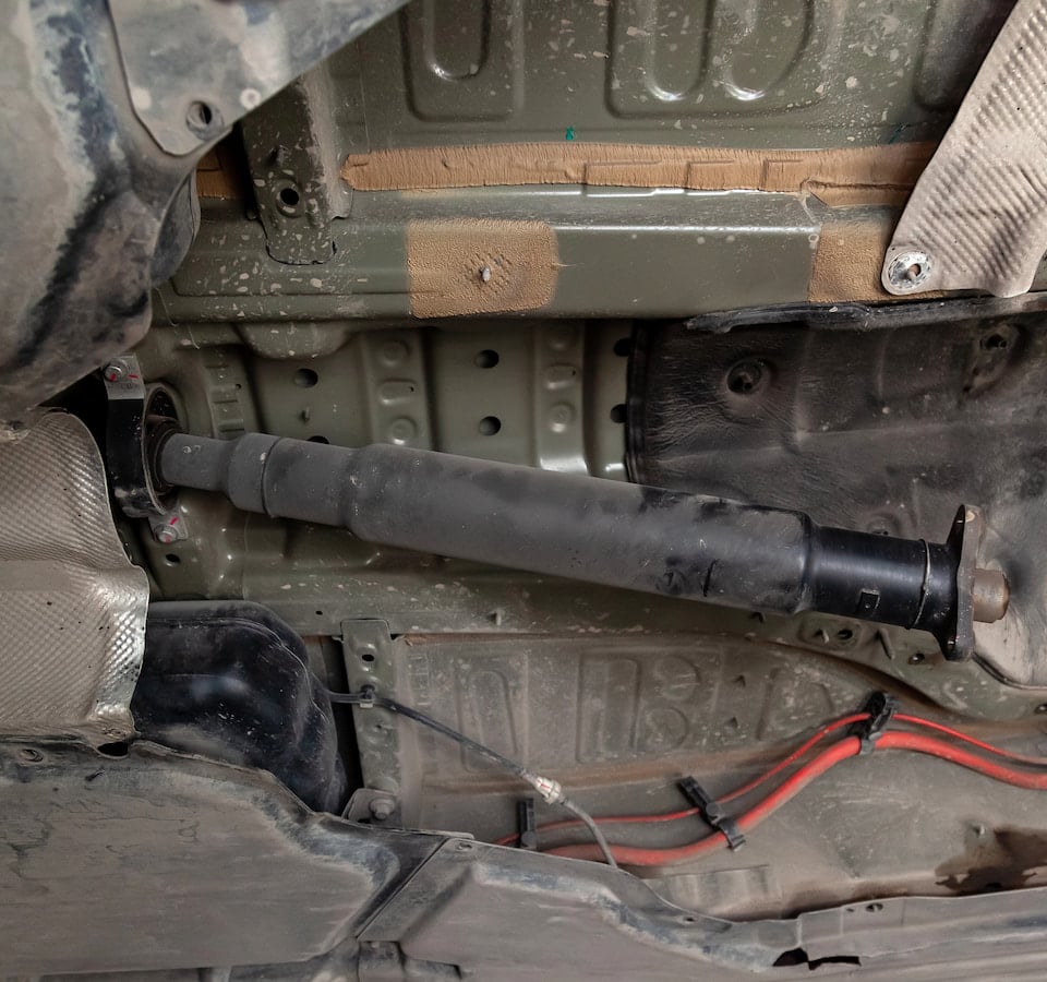 Auto Drive Shaft Repair Denver image Vehicle undercarriage with driveshaft and exhaust components