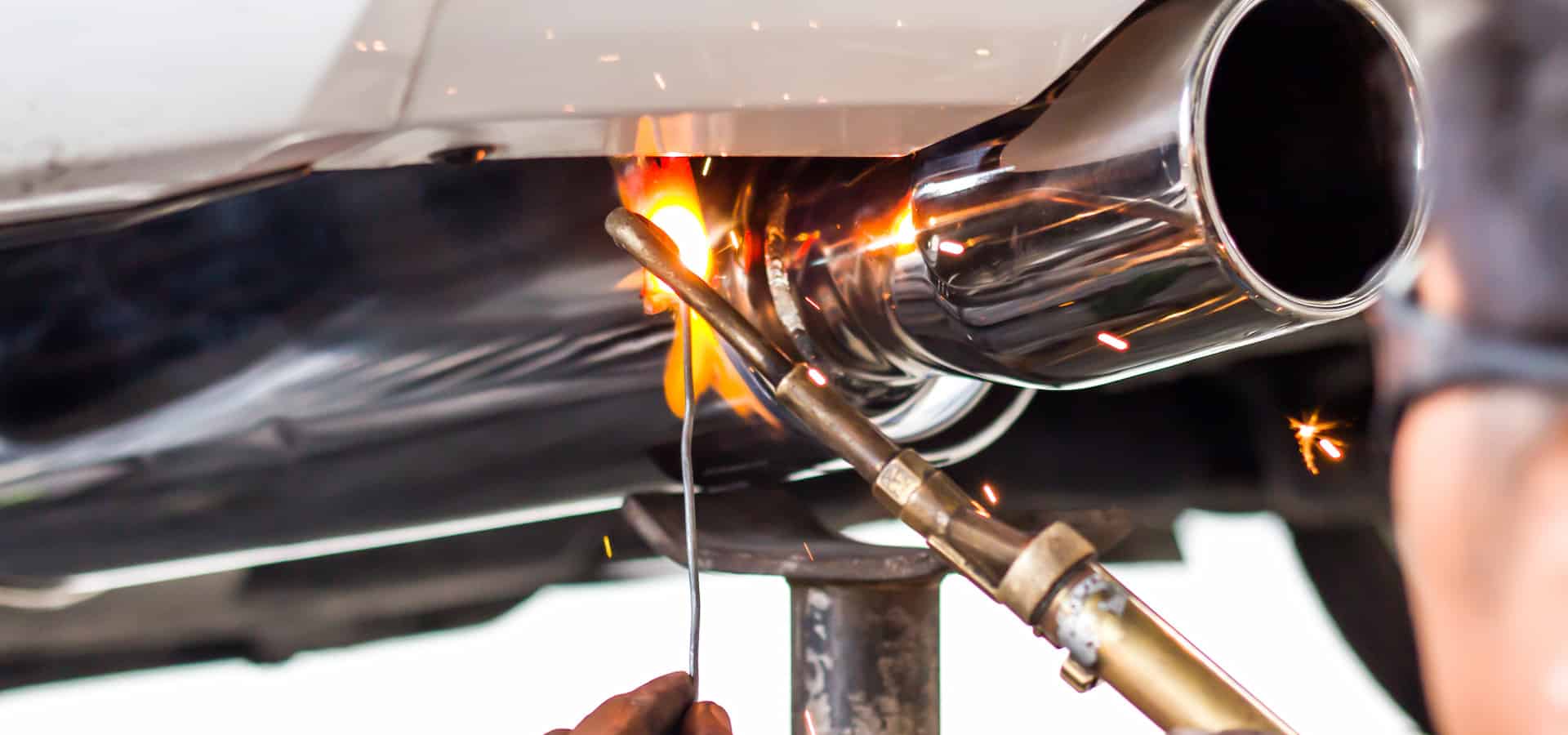 Welding car exhaust pipe with torch and sparks