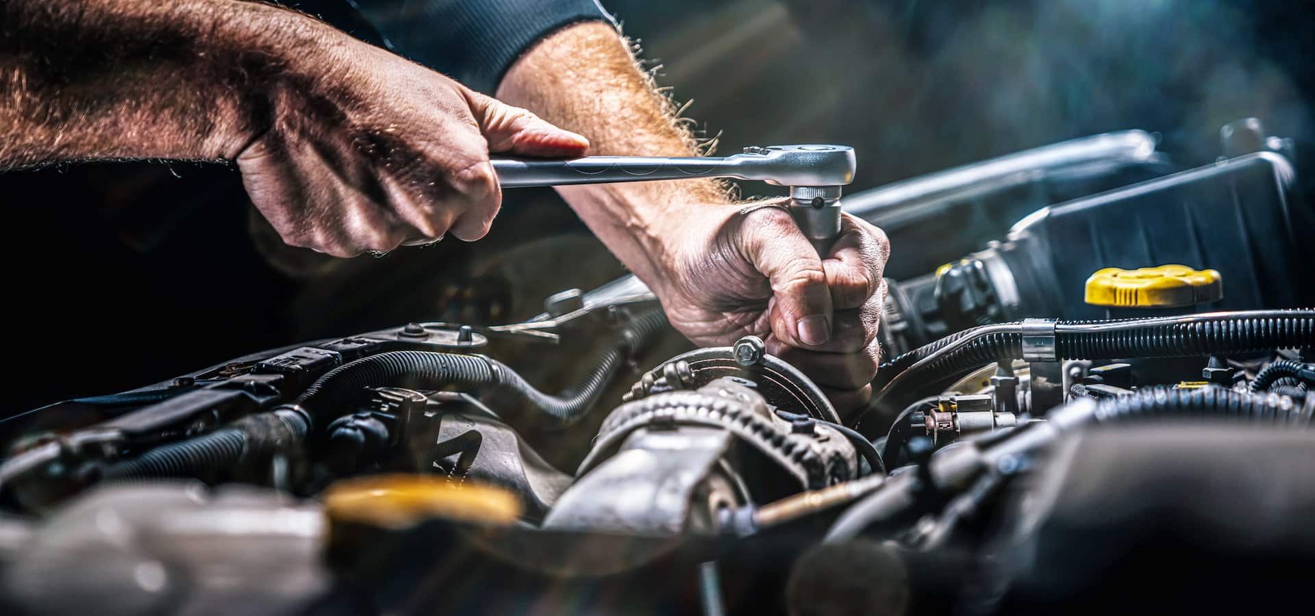 Mechanic tightening bolt in car engine bay