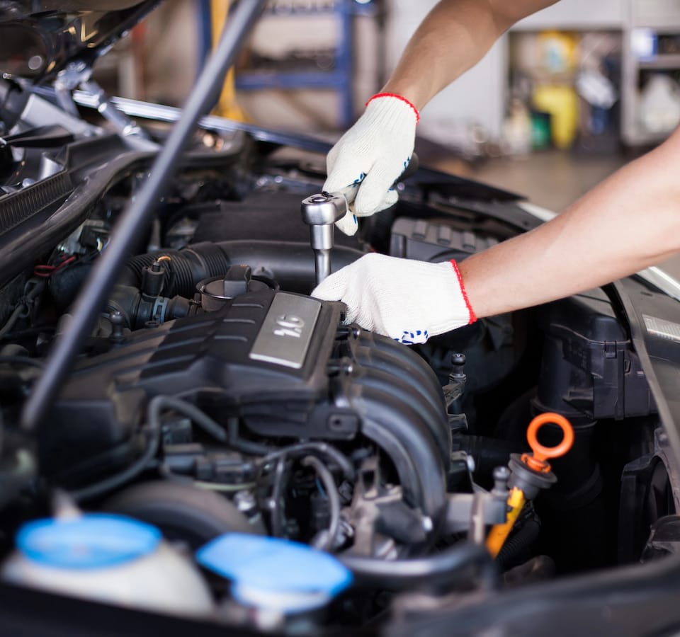 Auto Head Gasket Repair & Replacement Denver image Mechanic using ratchet on car engine