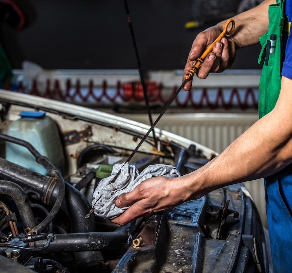 Auto Oil Change Denver image Mechanic checking car oil with dipstick