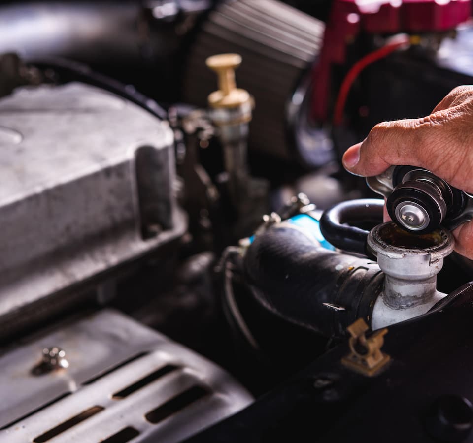 Auto Radiator, Thermostat, Water Pump Repair Denver image Hand pouring coolant into car radiator