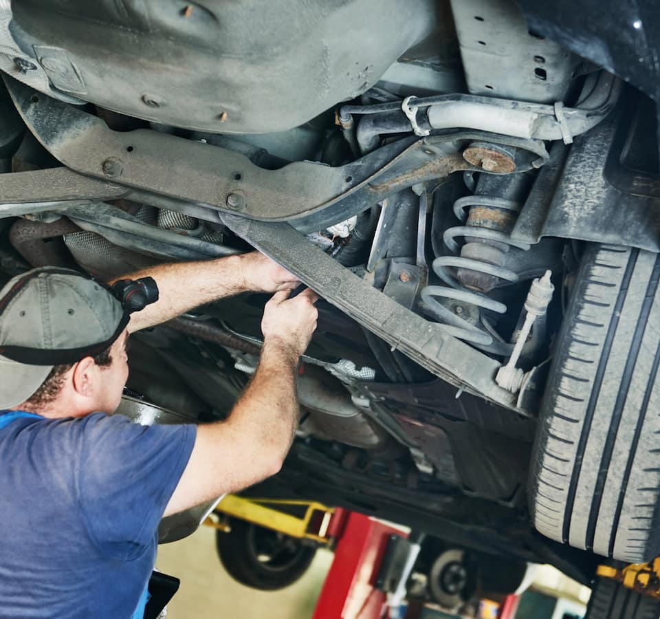 Auto Suspension Repair Denver image Mechanic repairing car suspension under lifted vehicle