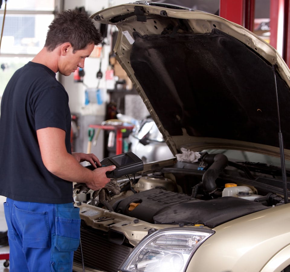 Auto Tune Up Denver image Mechanic using diagnostic tool under car hood